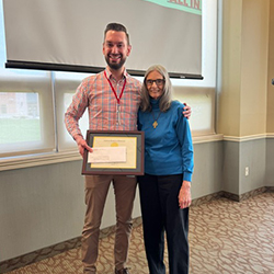 Adam Potter smiles while receiving award