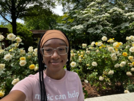 Anaya smiles in a selife while in front of some flowers.