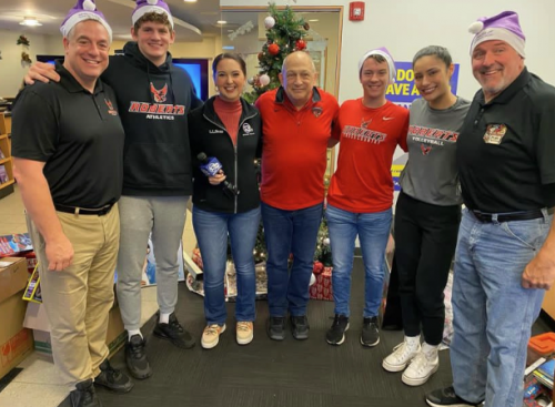 A group of students and staff smile at the toy drive