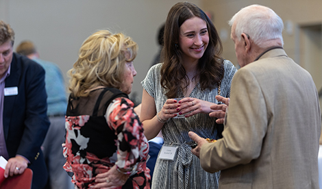 A student smiles while having a conversation with 2 donors