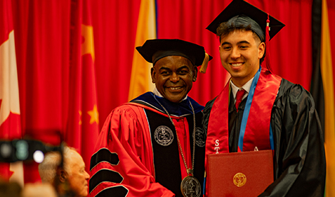 Dr. Hayles smiles with a graduate holding their diploma