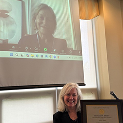 Elenice Lima smiles on screen while award is presented to her