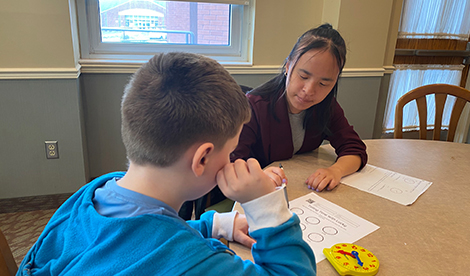 A Roberts student works on a worksheet with an elementary student