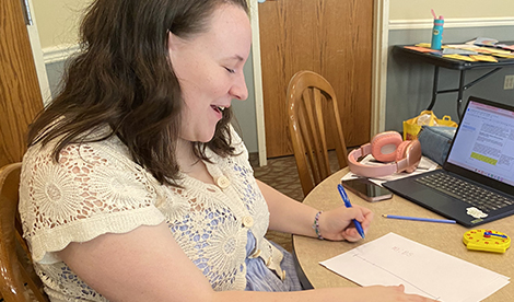 A Roberts student smiles while looking down at a piece of paper she's working on