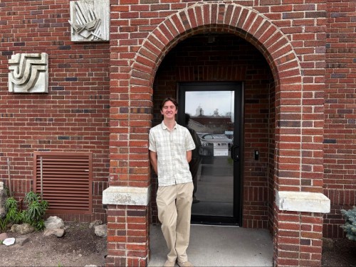 Eliott stands and smiles on campus
