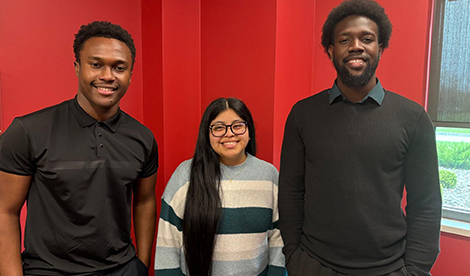 3 students stand and smile