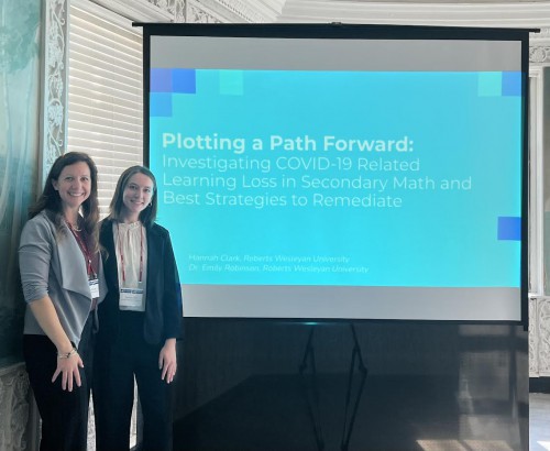 Emily Robinson and Hannah Clark stand in front of Clark's presentation.