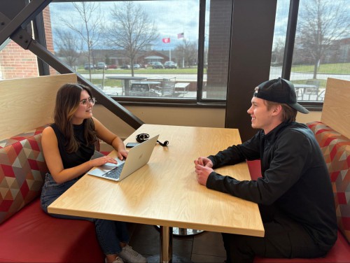 Jenna and a classmate work on a project together. She has a laptop open in front of her.