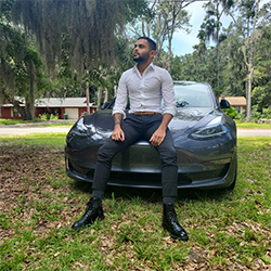 Kelvin Velez leans against the front of a car