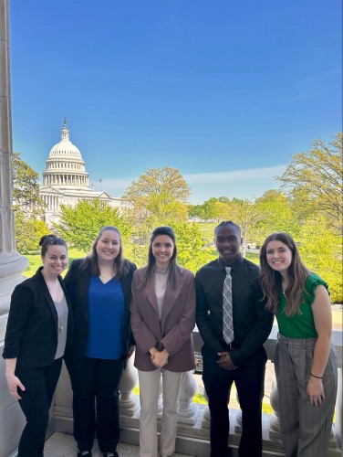4 students and a professor stand and smile