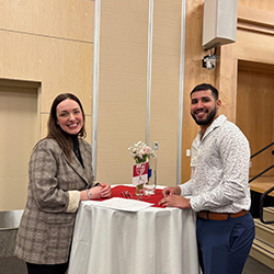 2 young adults stand at a table and stand