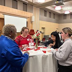 Students and a professional stand around a table together.