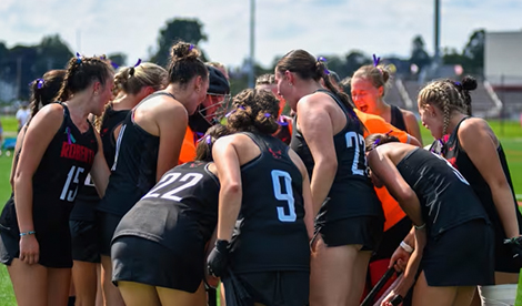 Women's field hockey team huddles together