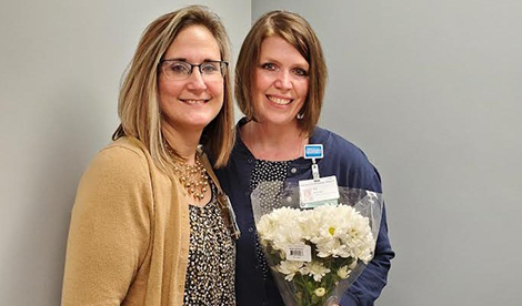 Tricia Woodward and a woman holding flowers smile together.