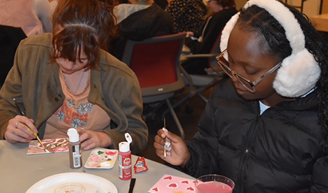 2 young women sit and paint