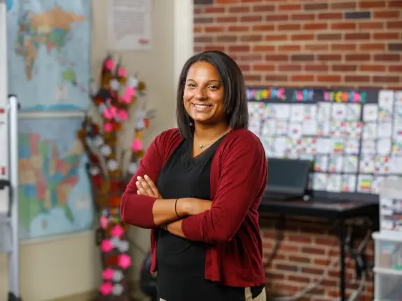 A teacher crosses her arms and smiles