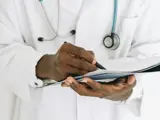 A medical professional writing on clipboard